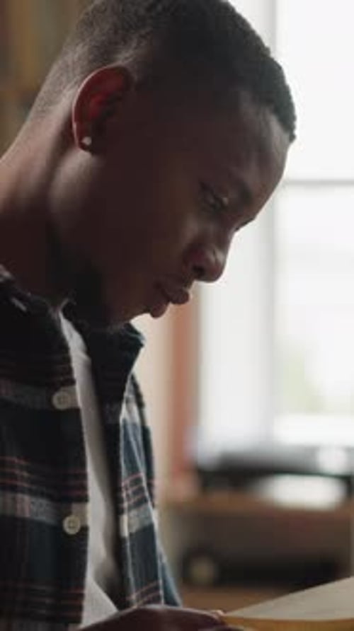 Young Man Reads Book in University Library