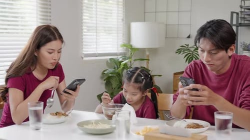 Family at Dining Table Using Smartphones While Eating