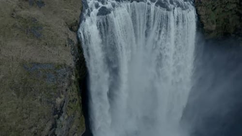 Slow descending aerial shot over powerful Skógafoss Waterfall iceland