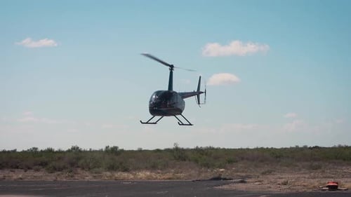 Hubschrauber nähert sich an einem sonnigen Tag einer Landung auf einer asphaltierten Landebahn in Zeitlupe