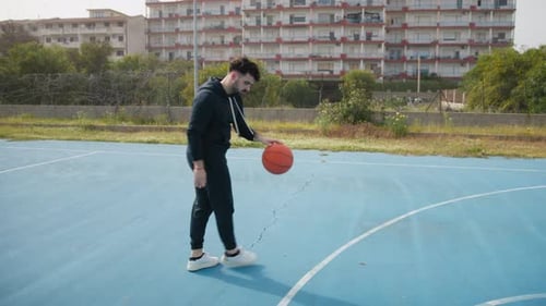 Un homme dribble un ballon de basket dans le parc