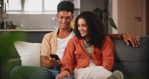 Couple Relaxing at Home on Sofa With Phone