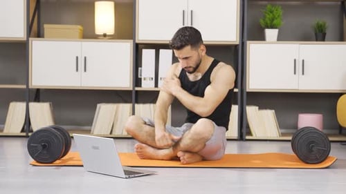 Young Man Stretching and Talking on Laptop