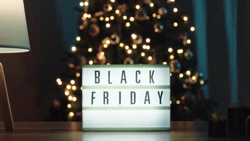 Black Friday sign near Christmas tree with gifts