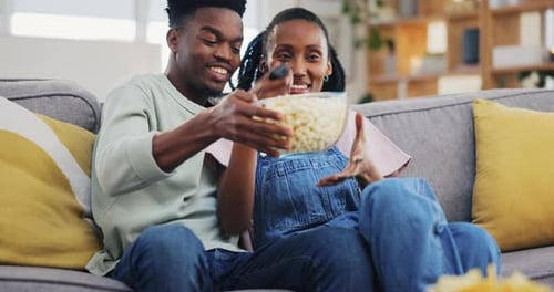 Couple Relaxing on Couch Enjoying Snacks and TV