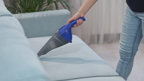 Close Up of A Woman with Handheld Vacuum Cleaning on Sofa