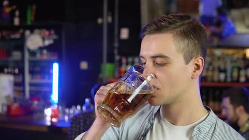 Porträt eines gutaussehenden kaukasischen jungen Mannes, der in einer Kneipe ein leckeres goldenes erfrischendes Biergetränk trinkt