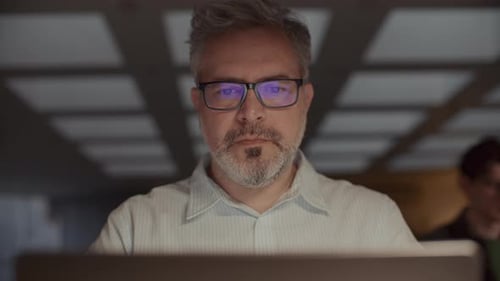 Empresário sênior trabalhando em laptop até tarde no escritório