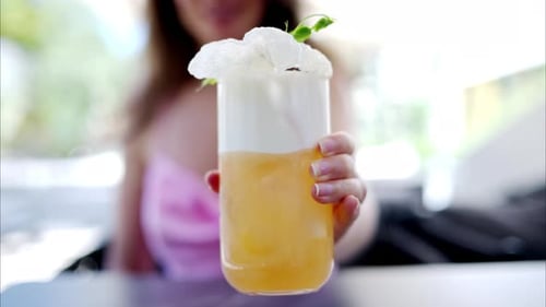 Woman holding a summer white and orange cocktail with whiskey and peach juice, slow motion