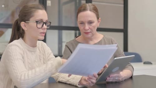 Women Review Documents and Tablet in Office