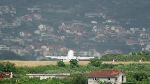 Airplane Landing on Runway Near Houses