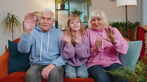 Grandparents and Child Waving Cheerfully on Couch