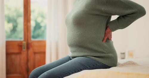 Woman Rubbing Aching Lower Back While Sitting