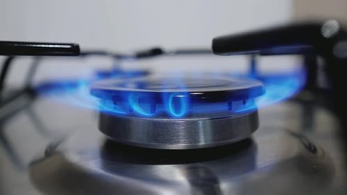Gas Burner Flame with Blue Glow on Stainless Steel Stove Surface