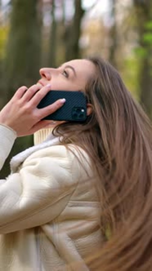 Junge hübsche Frau hat einen Anruf. Fröhliche Dame im Freien beim Telefongespräch. Vertikales Video