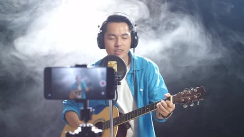 Man Singing and Playing Guitar in Studio