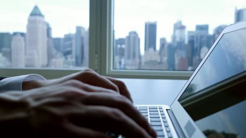 Man Working on Laptop with City View
