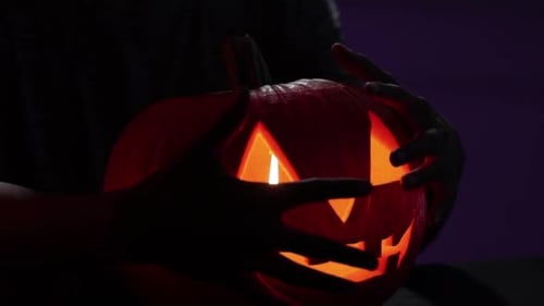 Spooky footafe of hands stroking a carved pumpkin for halloween season. October decoration. Fixed ca