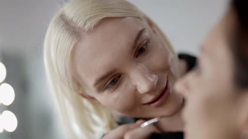 Professional Makeup Artist Drawing on Female Face in Beauty Studio Preparing to Fashion Show