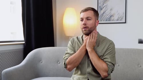 Man Touching his Sore Throat Indoors