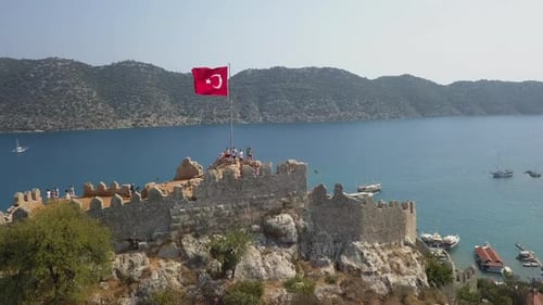 Die Ruine der Burg Simena auf einem Felshügel umkreist die Flagge der Türkei