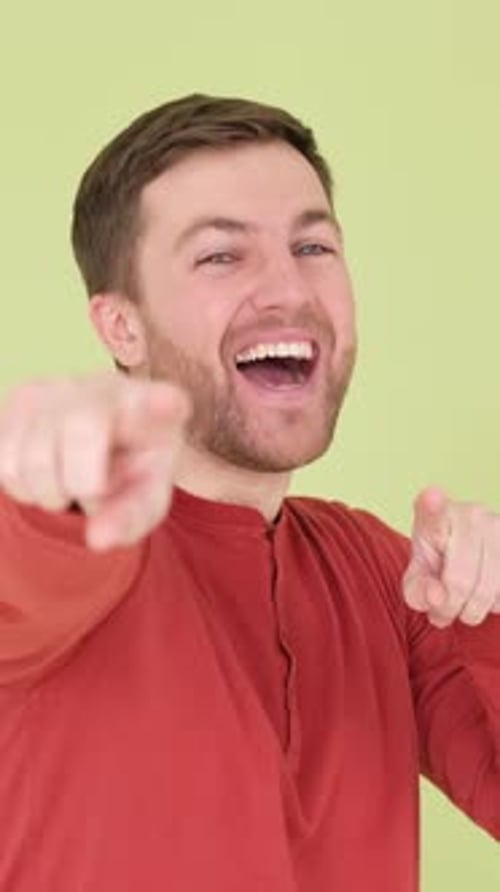A Handsome Man Points His Fingers at the Camera He Stands on the Background in the Studio