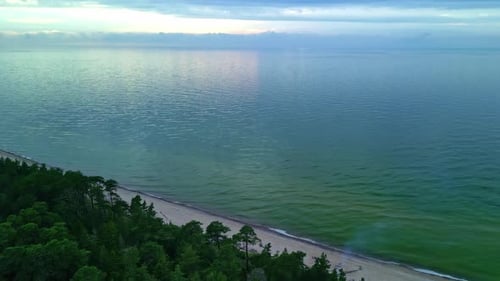 Aerial drone reveal shot of a remote empty beach on a cloudy day