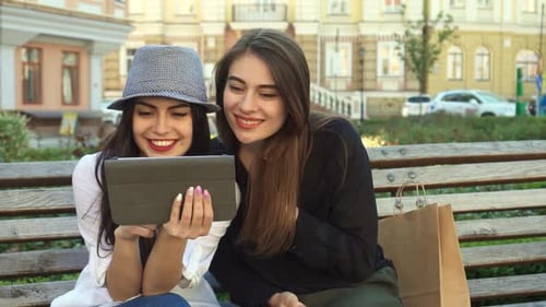 Two Stylish Female Friends Enjoying a Tablet Outdoors in the City