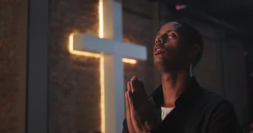 Man Praying in Church near Glowing Cross