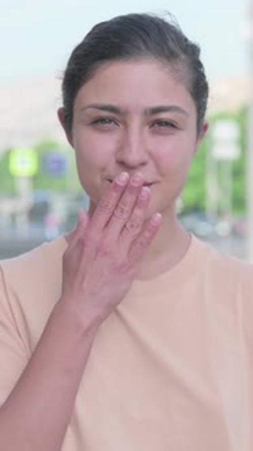 Smiling Woman Blows Kiss in Urban Environment