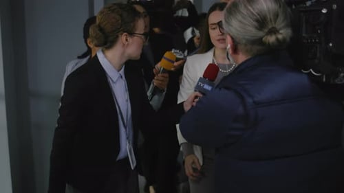 Woman Giving Press Conference Surrounded by Reporters