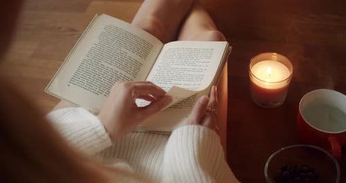 Person Reading Book with Candle and Berries