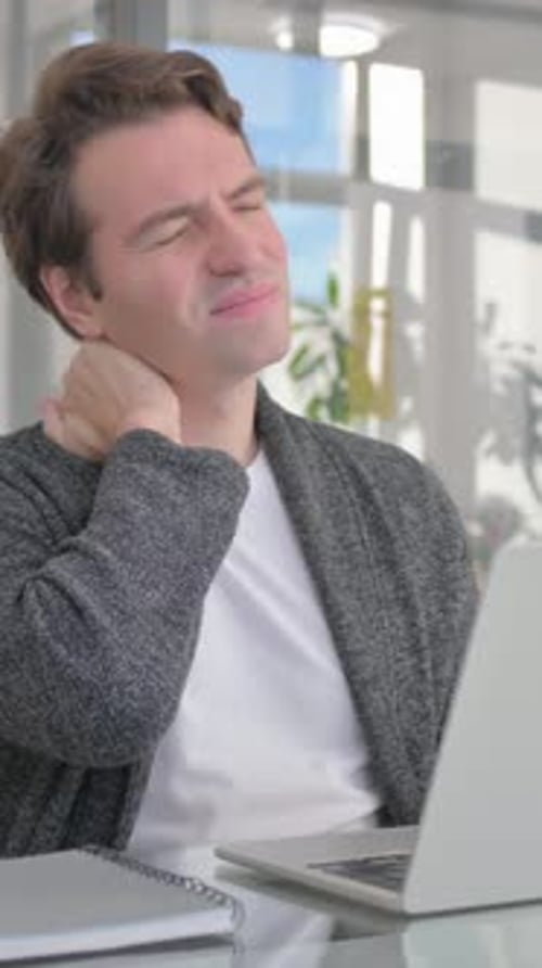 Young Man having Neck Pain in Office, vertical video