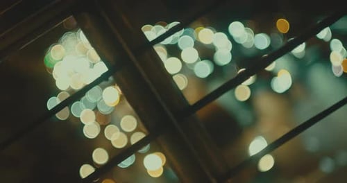 Defocused Vehicle Headlights Behind Steel Barrier. City Night Traffic.