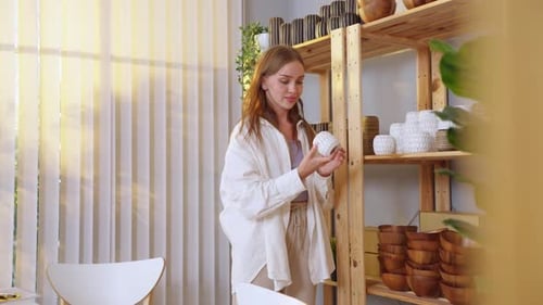 Caucasian young woman packing vase goods order into box for customer.