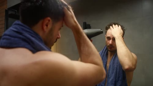 Caucasian man drying hair with a hairdryer