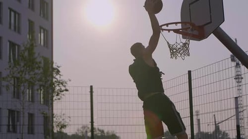 Athletic man practices basketball skills on outdoor court