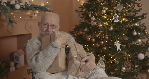 Senior Man Holding Christmas Gifts in Wheelchair