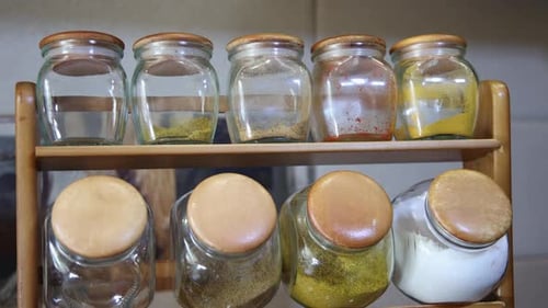 Surtido de tarros de cristal para especias almacenados en un estante de cocina de madera
