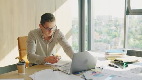 A Dedicated Businessman in a Cluttered Office is Focused on Work and Driven By Success As He Gazes