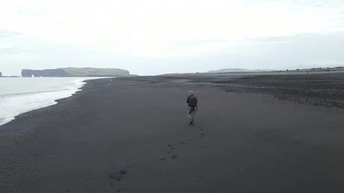 Lonely manwalking on the beach of Iceland, Reynisdrangar, aerial