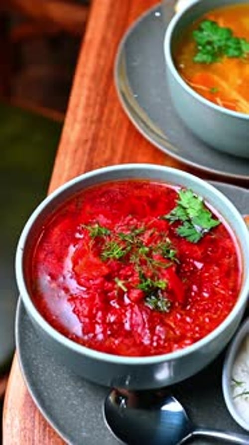Red broth with dill garnish. Deep red broth with dill and parsley served with bread