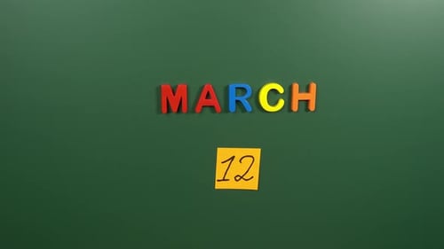 Hand sticking a sticker 12 March calendar day on school board. 12 date of March. Twelfth day