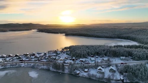 Aerial view of a snow-covered village on a frozen lake shore