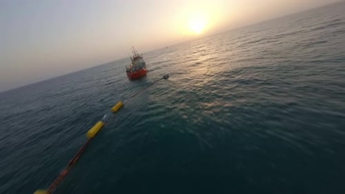 Paysage marin au coucher du soleil avec barrière flottante et navire