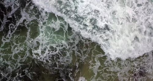 4K Hovering above hypnotic water crashing on shoreline