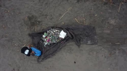 Freiwillige werfen Müllmüll von der Strandreinigung auf eine Plane im Sand