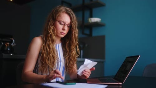 Woman Reviews Finances with Receipts and Laptop