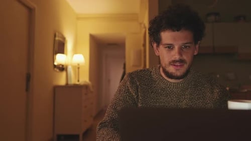 Man Works on Laptop at Night, Drinks Coffee
