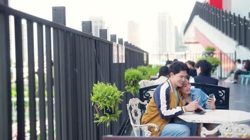 Asian couple using mobile phone with credit card booking hotel or online shopping at street market